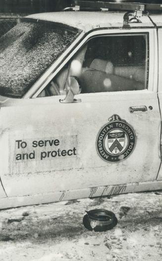 Christmas Eve tragedy: A policeman's cap and blood on cruiser mark spot where two officers were wounded in a gun battle