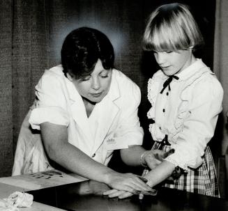 Getting printed: Lori McKay, 10, gets her finger and palm prints taken by Kim Berry at the Child Find group's booth in the show A Time for Children, on at Exhibition Stadium this weekend