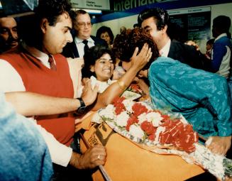 Welcome home: Relatives cluster around Shainaz Bhatia to shower her with hugs and kisses as she arrives at Pearson airport last night with her husband, Arif Gulamani, both on stretchers