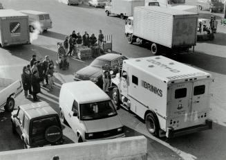 Daylight heist: Workers at the Ontario Food Terminal in Etobicoke stare at a Brink's truck whose guard was robbed by two yesterday