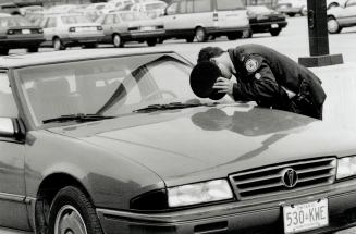 Getaway car: Metro police examine the getaway car left at Lawrence Square Plaza by two gunmen who robbed a Brink's guard yesterday