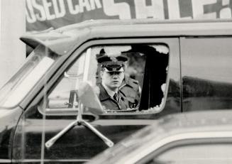 Windows shattered: A police officer looks through windows on the driver and passenger side of a van shot out by a shotgun blast yesterday, after a gun was pointed at a policeman