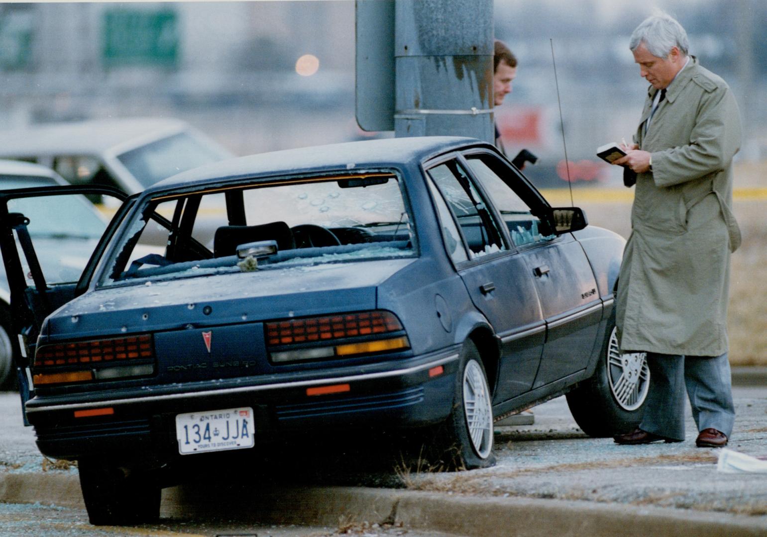 Bullet-peppered car: Police check getaway car, its rear windows shot out and windshield bullethole-ridden, after a shootout early today with three holdup suspects in Etobicoke