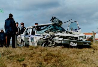 Heavy damage: Officers survey the Peel Region police cruiser stolen from a constable yesterday by a man who later crashed on Highway 401 near Dixon Rd