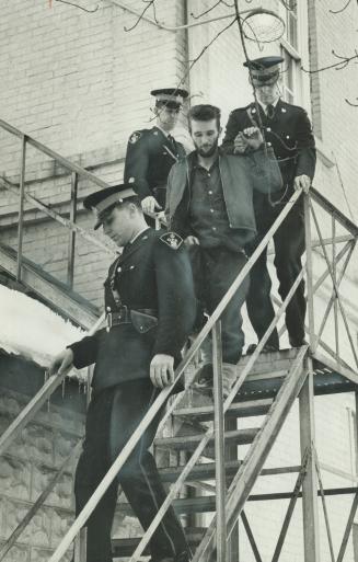 Three Off Officers escort murder suspect William Norman Pratt, 35, down back fire escape of the Lindsay court house today. [Incomplete]