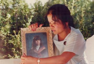 Relying on prayer: Julita Bain, mother of missing U of T student Elizabeth Bain, 22, holds her daughter's photo yesterday after a prayer vigil attended by hundreds