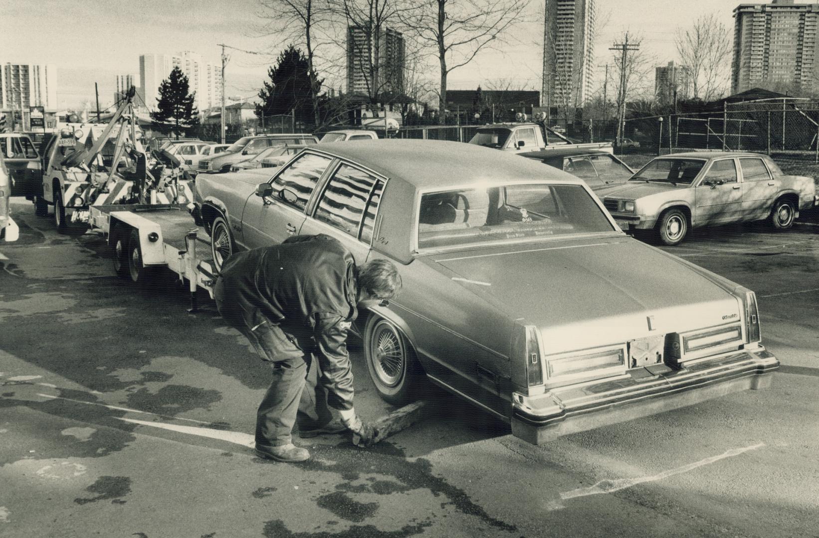 Death car: With the body of a slain man still in the trunk, an Oldsmobile is loaded on to a flatbed trailer to be taken to the Centre of Forensic Sciences today