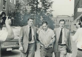 John McBeth Finlayson, 37, the object of a nation-wide search in the mutilation-killing of 9-year-old Kirkland Deasley, is escorted into Metro police (...)