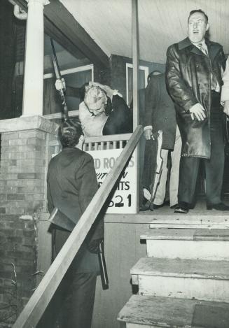 At house on Madison Ave. where two suspects shot themselves in a teargas-filled room, Inspector David Cowan (at top of steps) directs policemen with t(...)