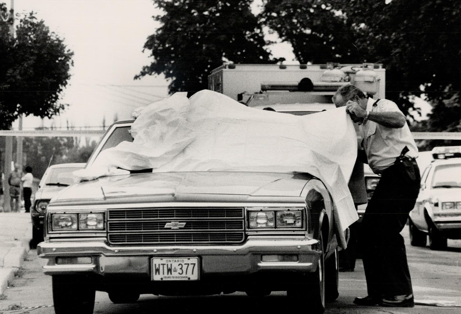 Murder vehicle: A homicide investigator examines a taxi whose driver was found slain behind the wheel on a quiet street in Toronto's west end