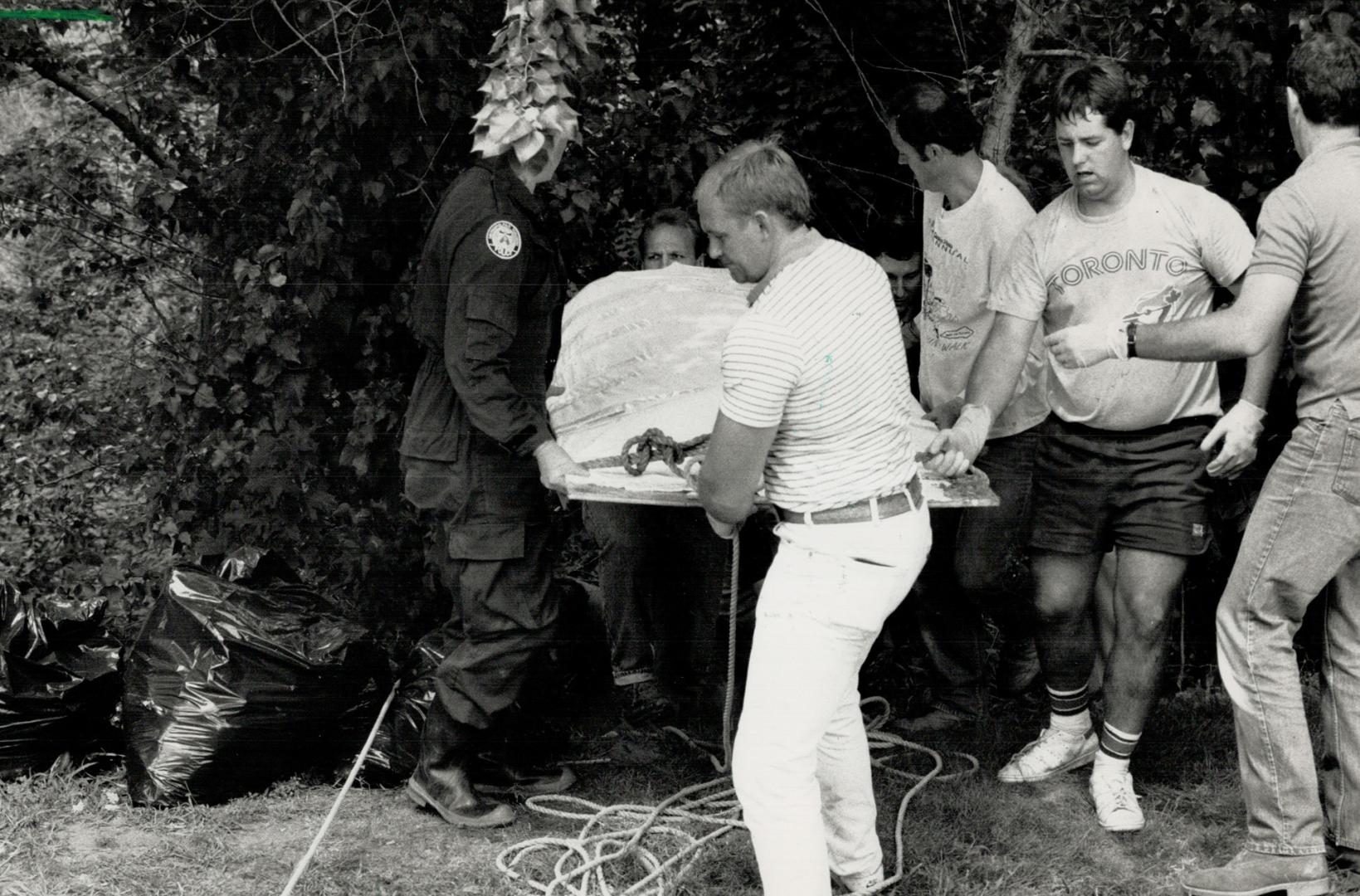 Grim Discovery: Metro police remove the badly decomposed body of missing librarian Susan O'Neal from an East York ravine yesterday