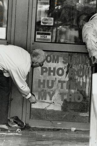 Fatal attack: Police check a bullet hole in a glass door yesterday during their investigation of three execution-style killings in Chinatown