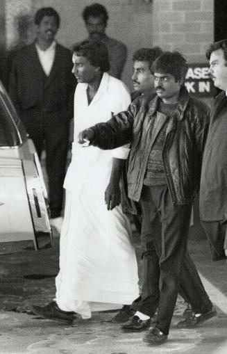 Time of grief: Sivaguru Srikantharajah, 32, left, father of Apirami, 1 1/2, and Aparinaa, 2 1/2 is accompanied to a waiting car after the funeral for his daughters