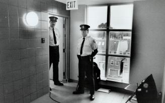 Under guard: Constables Steve Nicolitis, left, and Paul Mackerel guard a door yesterday at the base of stairs leading to the maintenance room where Andrea Atkinson's body was found