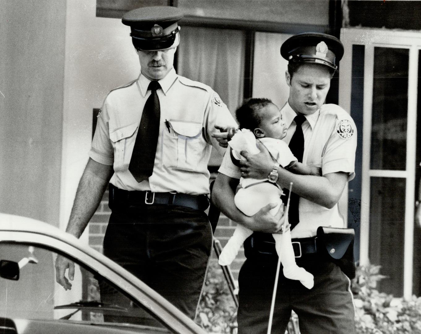 Police bring out one of the babies found in the apartment where the stabbing took place