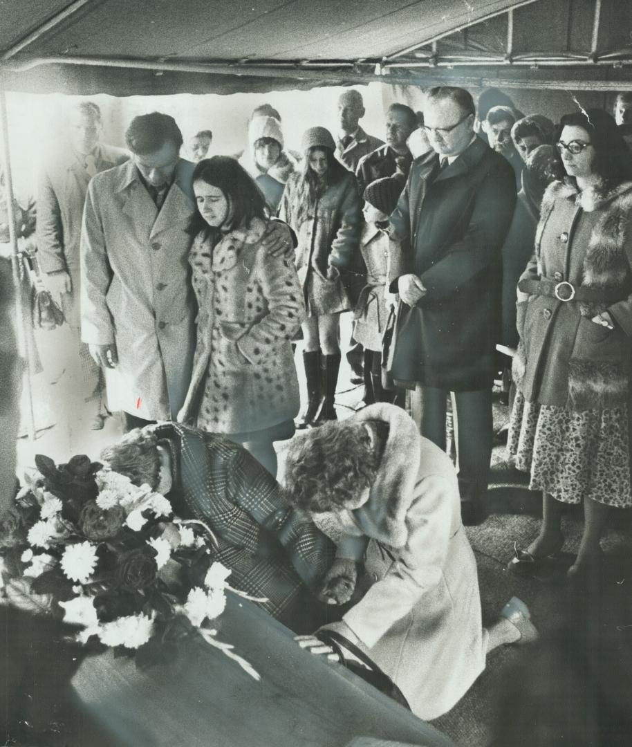 Sorrowing relatives surround Peggy Stoddart (checked coat) as she kneels at the coffin of her husband, Gordon, at his burial today in Pine Hills cemet(...)