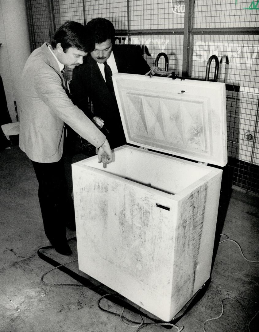 Gathering evidence: Inspector Mike Metcalfe (left) and Staff inspector Noel Cartney of the Peel Regional Police examine in freezer in which the body of a woman was found Wednesday night