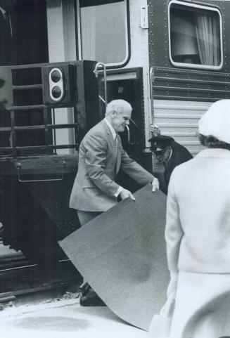 Ontario Corrections Minister Syl Apps, a former Maple Leaf star, moves the red carpet at Kingston station to the door the Queen was to leave the train(...)