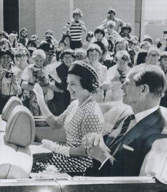 The Queen, accompanied by Prince Philip, waves to the smiling crowd lining the streets of St