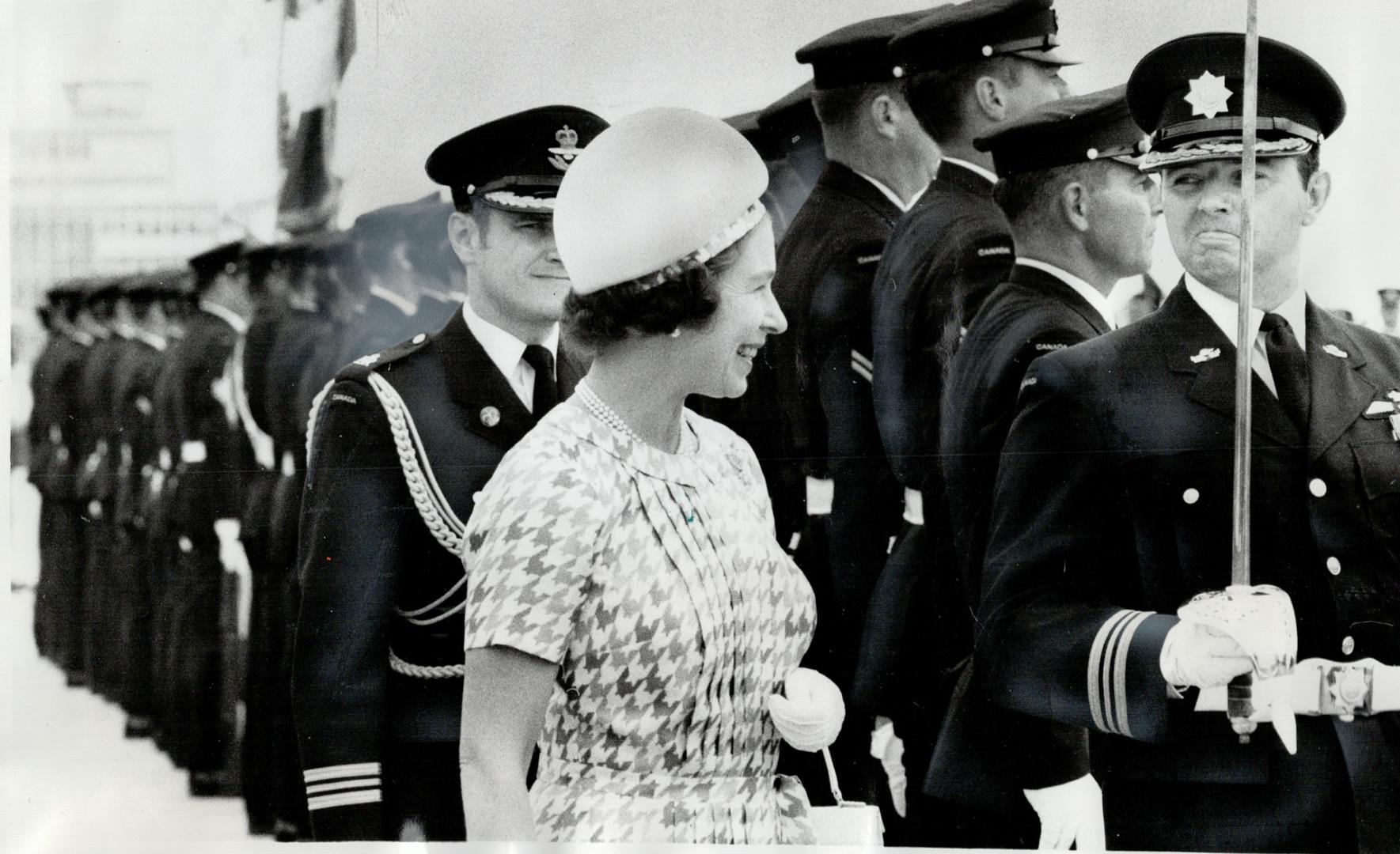 Royal salute - and a grin fit for a Queen, The Queen inspects a Royal Canadian Regiment guard of honor, as one member presents arms, on her arrival at Ottawa, yesterday