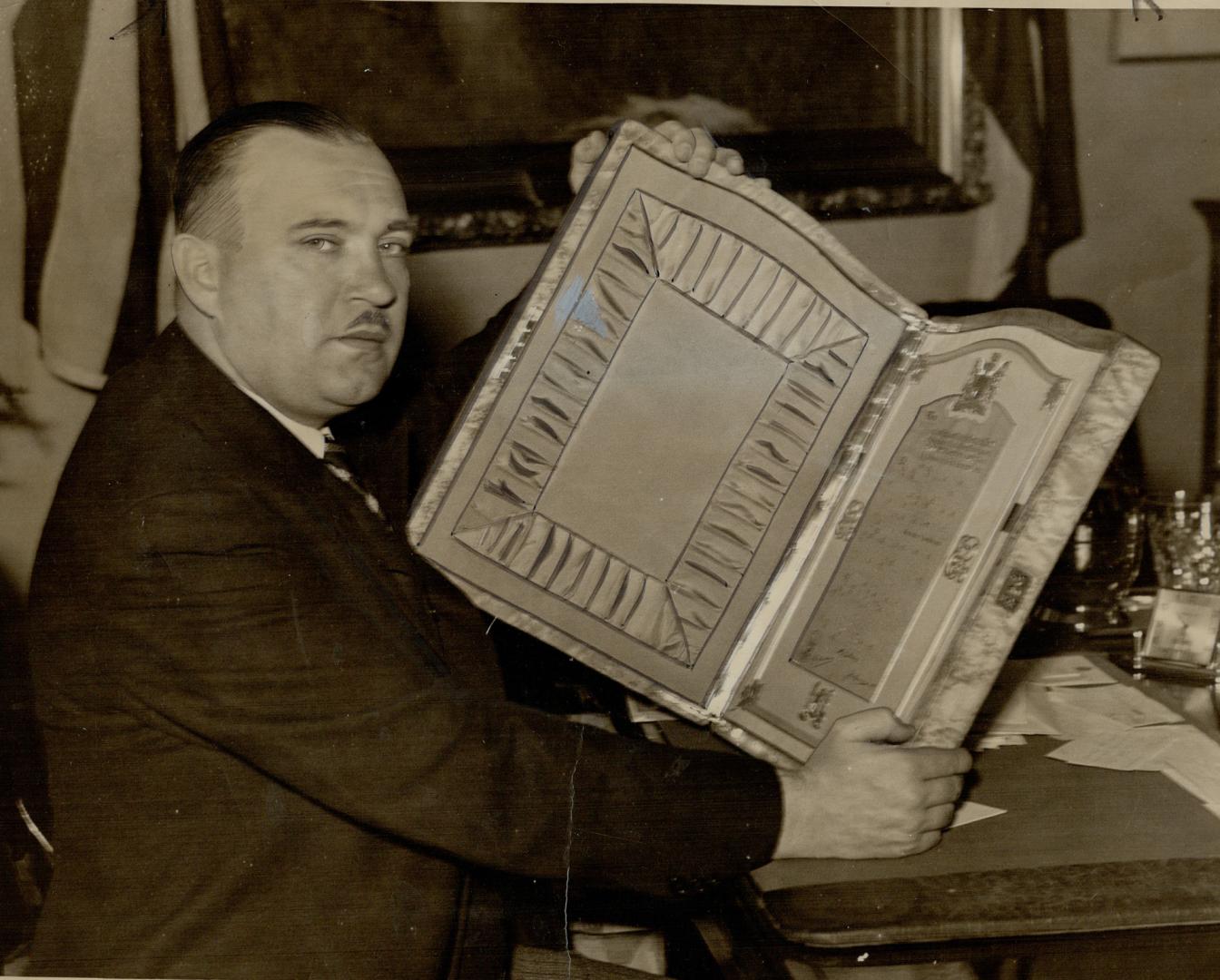 To his most excellent Majesty George The Sixth-, Mayor Day displays the gold and silver plaque which will carry Toronto's official greeting to the King