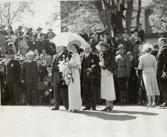 Carrying a parasol the Queen, right, watched the impressive ceremony as sailors from Canada's fighting ships formed a hollow square about the traditio(...)