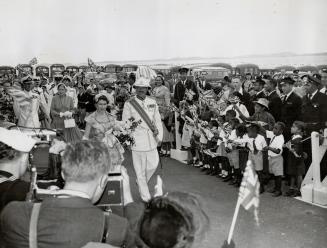 The Queen accompanied by Sir Alexander Hood, Governor of Bermuda, is greeted by flag-waving children