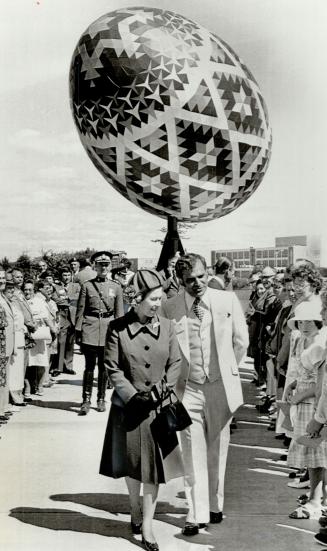 Under a giant Easter egg, the Queen chats with council members at Vegreville, Alta