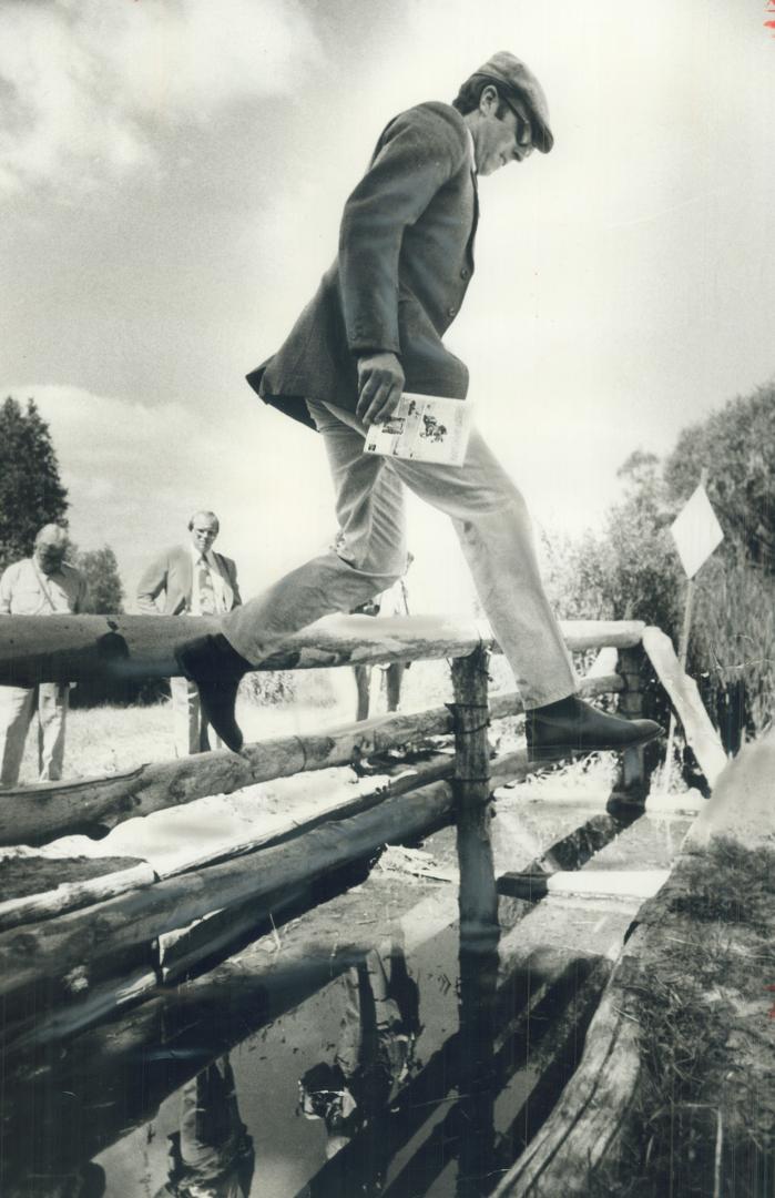 Mark Phillips inspects a cross-country racecourse at a farm near Aurora, while his mother-in-law, the Queen, chats with war veterans in Deer Lake, Nfld