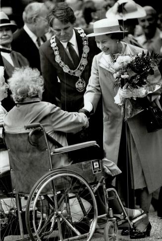 Queen shake hand of senior citizen folow by mayor Gordon Campbell during her downtown walkout today after opening of science world exibit