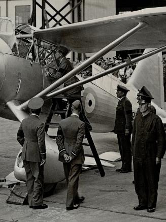 The king's air tour-The King climbing a ladder to inspect the cockpit of a bomber at Martlesham Heath aerodrome during his recent tour of air centres of England by aeroplane with the Duke of York