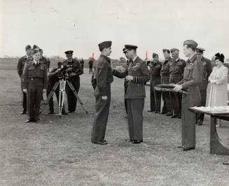 The King pins the D.F.C. on the breast of Flt.-Lieut. Don MacFadyen. Chestnut Park Rd., Toronto, who has six confirmed, two probables and nine damaged, enemy aircraft to his credit