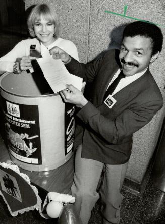 Couple of winners. Model Bonny Barrett and Clyde Gray, Ontario Athletics Commissioner, draw winning tickets in The Star lobby for dinner at two Toront(...)