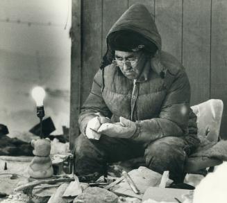 Broughton Island, 6 AM. Kooveuk Watsiapik sits in front of his house in the snow carving snipes out of soapstone