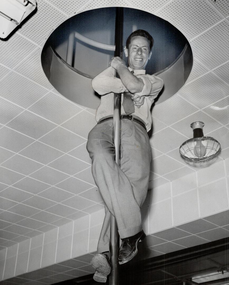 Reeve Gus Harris slides down the firemen's pole of the modern $80,000 firehall at Birchmount Rd