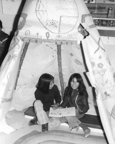 Children reading in a paper tepee