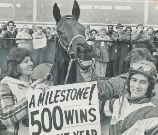 Sandy Hawley and his wife, Sherrie, hold sign at Laurel proclaiming realization of the goal Hawley set for himself last New Year's Eve, to ride 500 wi(...)