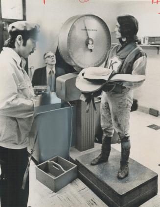 Weighing in, jockey Sandy Hawley holds his saddle and tack