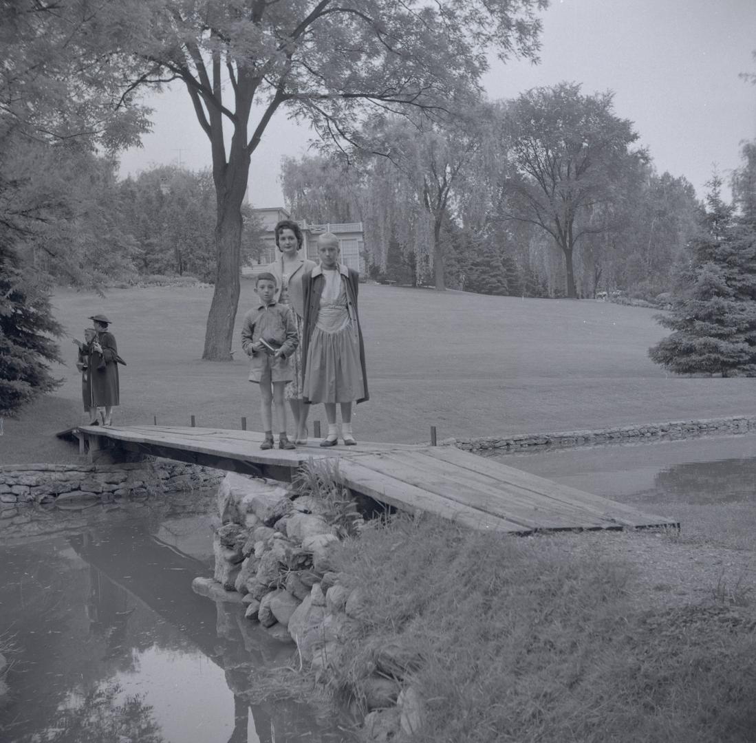 Image shows three family members posing for a photo on the bridge in the Edward Gardens.