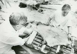 A man and woman stretching a hide