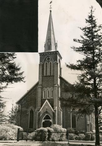 Front of church; entrance below belfry tower and spire. Lancet windows either side of entrance.…