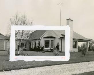 Brick and clapboard bungalow with evergreen hedges around foundation and shrubs on lawn.