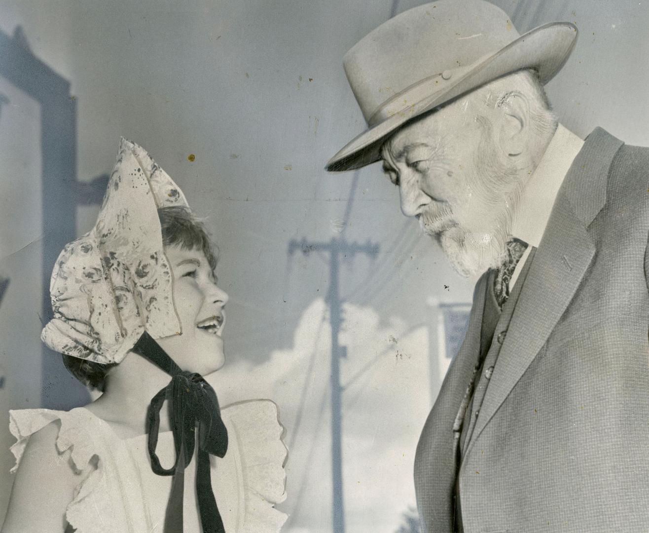 Dr. George McCartney, 92, oldest living native son, chats with Carol Church, who is trying out an old-fashioned bonnet to be worn during the centennial