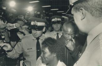 Guarded return: Ben Johnson and his mother, Gloria, are escorted past reporters by RCMP on their return to Toronto