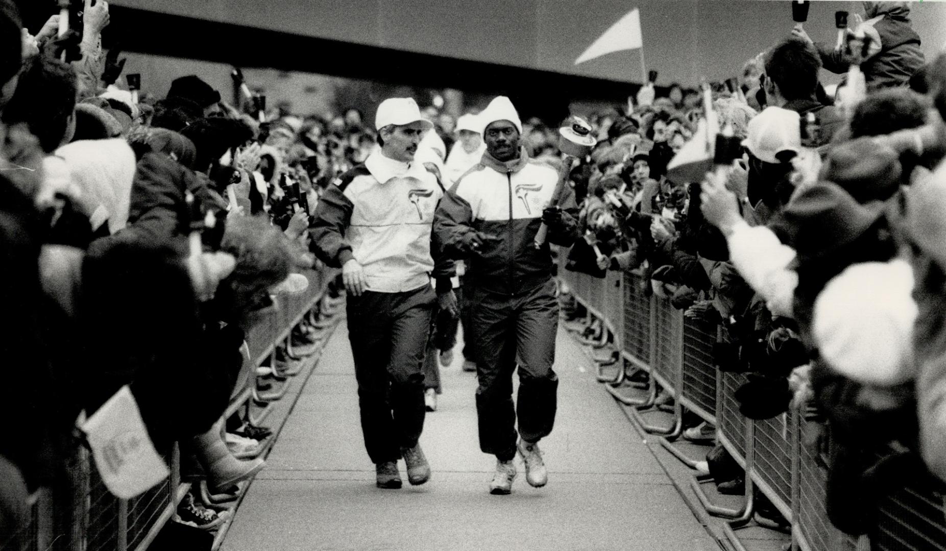 World champion sprinter Ben Johnson is greeted by the downtown throng as he runs with the torch to the reception ceremony, triggering Metro's Olympic passion