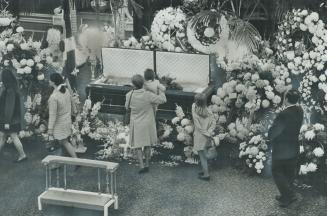 Saying a final farewell to Québec Premier Daniel Johnson, a mother lifts her daughter so she can get a better view yesterday as thousands of Québecker(...)