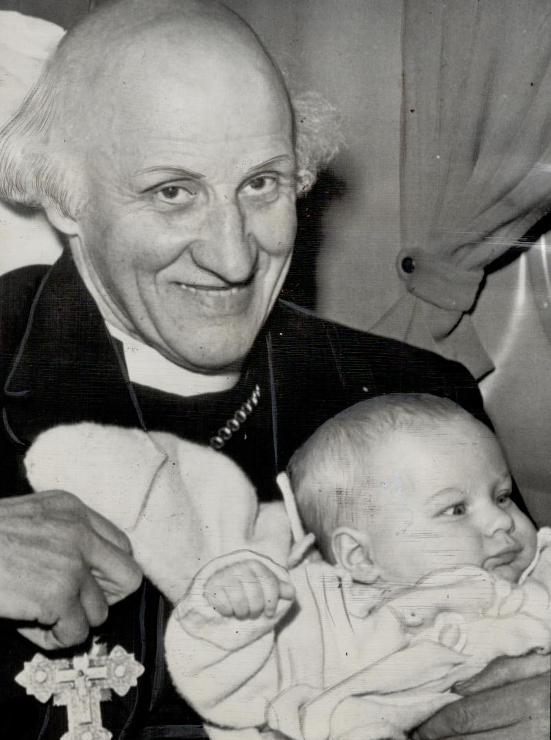 Hewlett Johnson, Dean of Canterbury, makes friends with a ng travel mate aboard his plane shortly before taking off from Bedford, Mass., for his return to London after visiting Toronto [Incomplete]