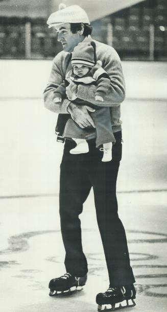 Cuddling baby E. J., Leaf goalie Eddie Johnston solemnly skates around the Gardens yesterday at Christmas party which resembled a giant nursery school