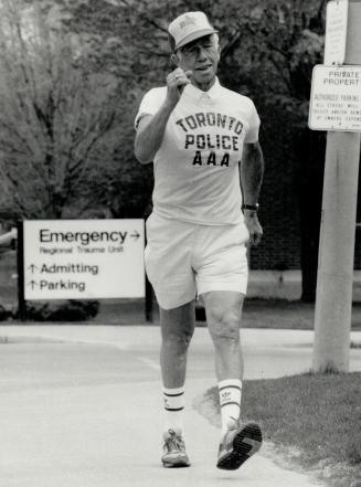 Image shows a gentleman walking a marathon. He is wearing a shirt that reads " Toronto Police".