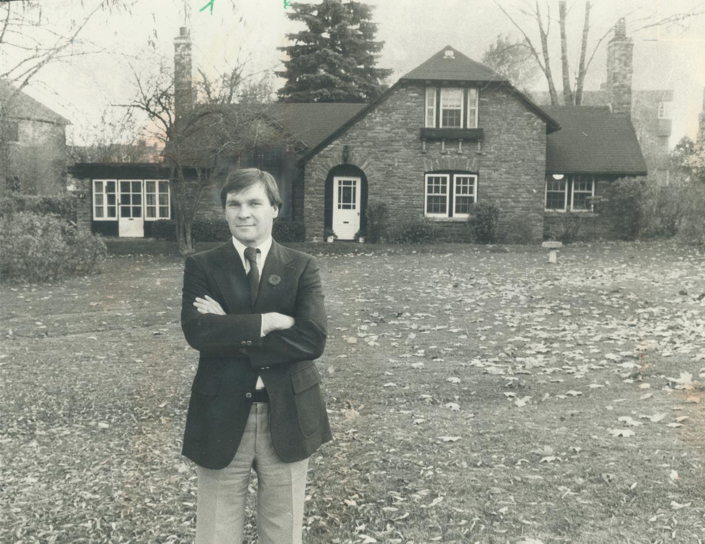 Alderman Morley Kells stands before house at 71 Old Mill Rd